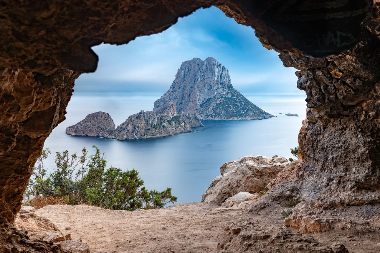 Portal de Es Vedrà, fotografia fine art de Bruno Boni. Enquadrado pelo portal rochoso de uma caverna, o mítico ilhéu de Es Vedrà surge sobre o Mediterrâneo sedoso, resultado…